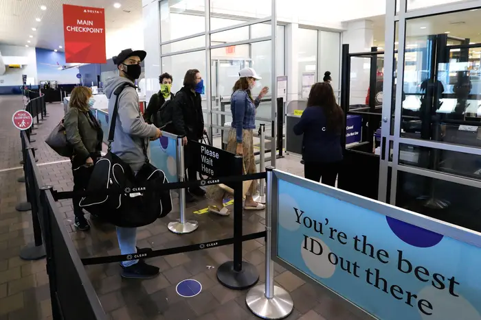 Travelers wearing face masks wait to pass through security at LaGuardia airport ahead of Thanksgiving.